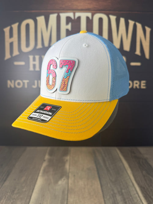 Colorful baseball cap with '67' design on a wooden surface with 'Hometown' background