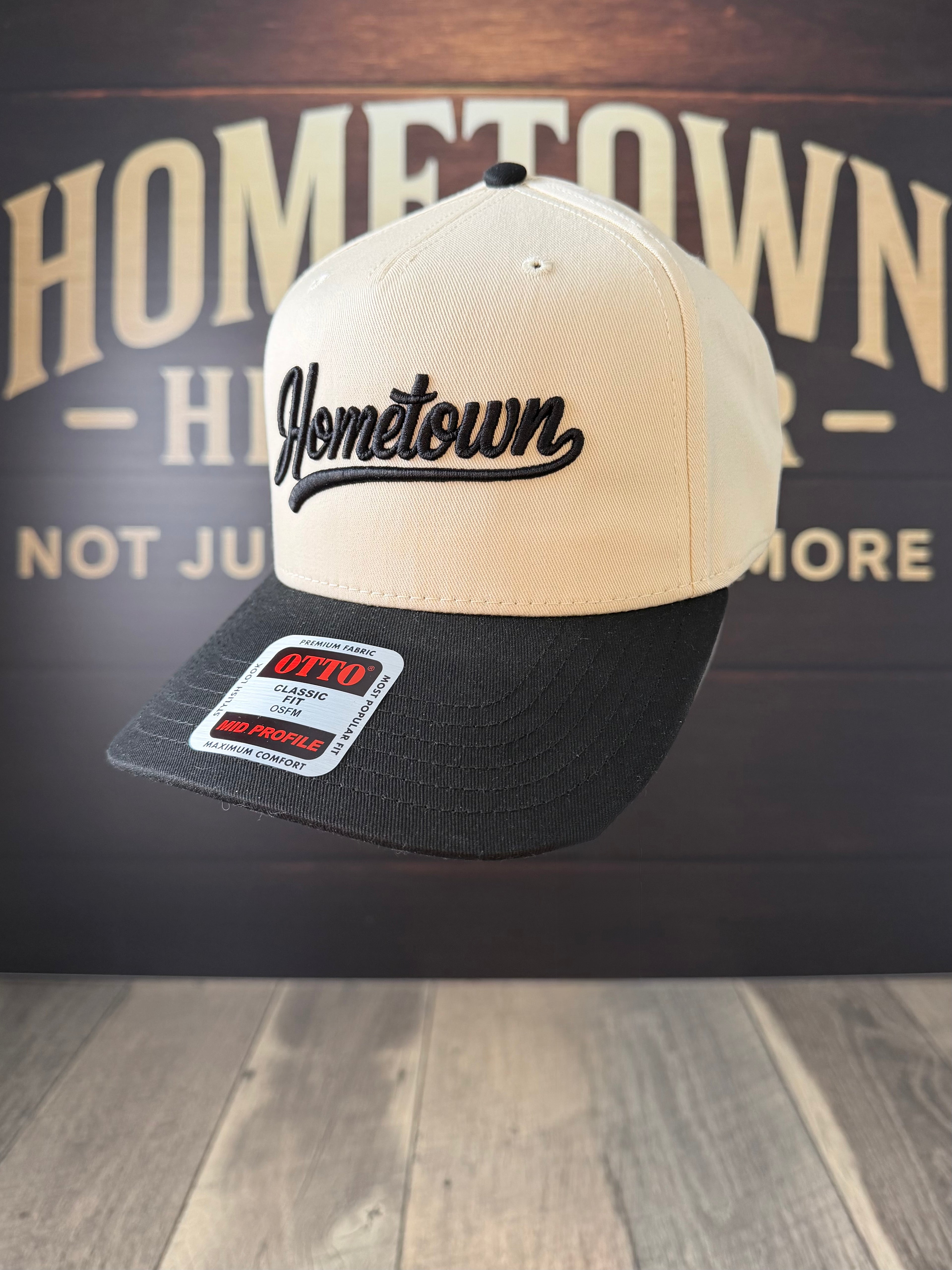 Two-tone cap with 'Hometown' branding on a wooden surface and dark background.