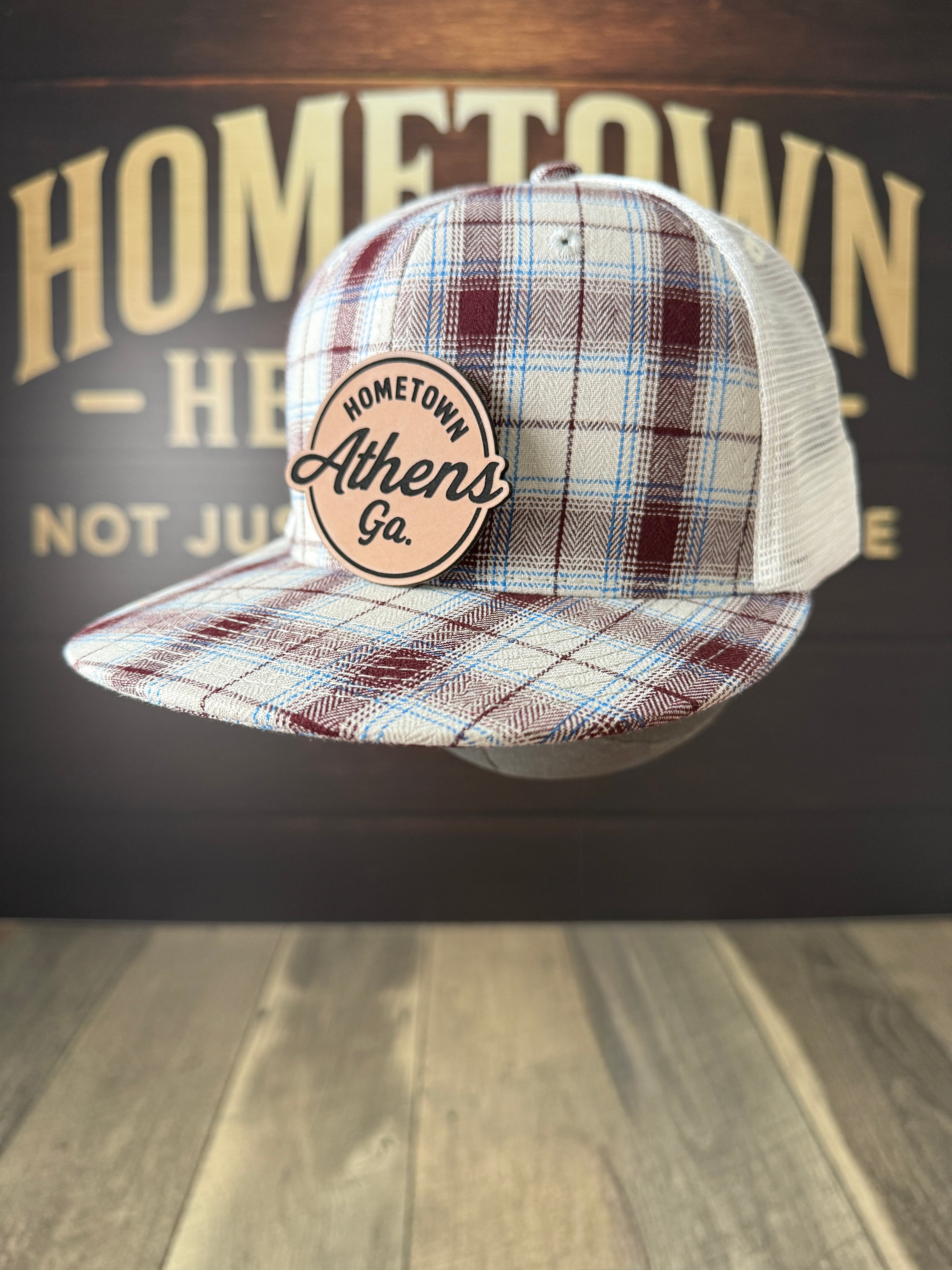 Plaid cap with 'Hometown Athens, Ga' logo against a wooden background
