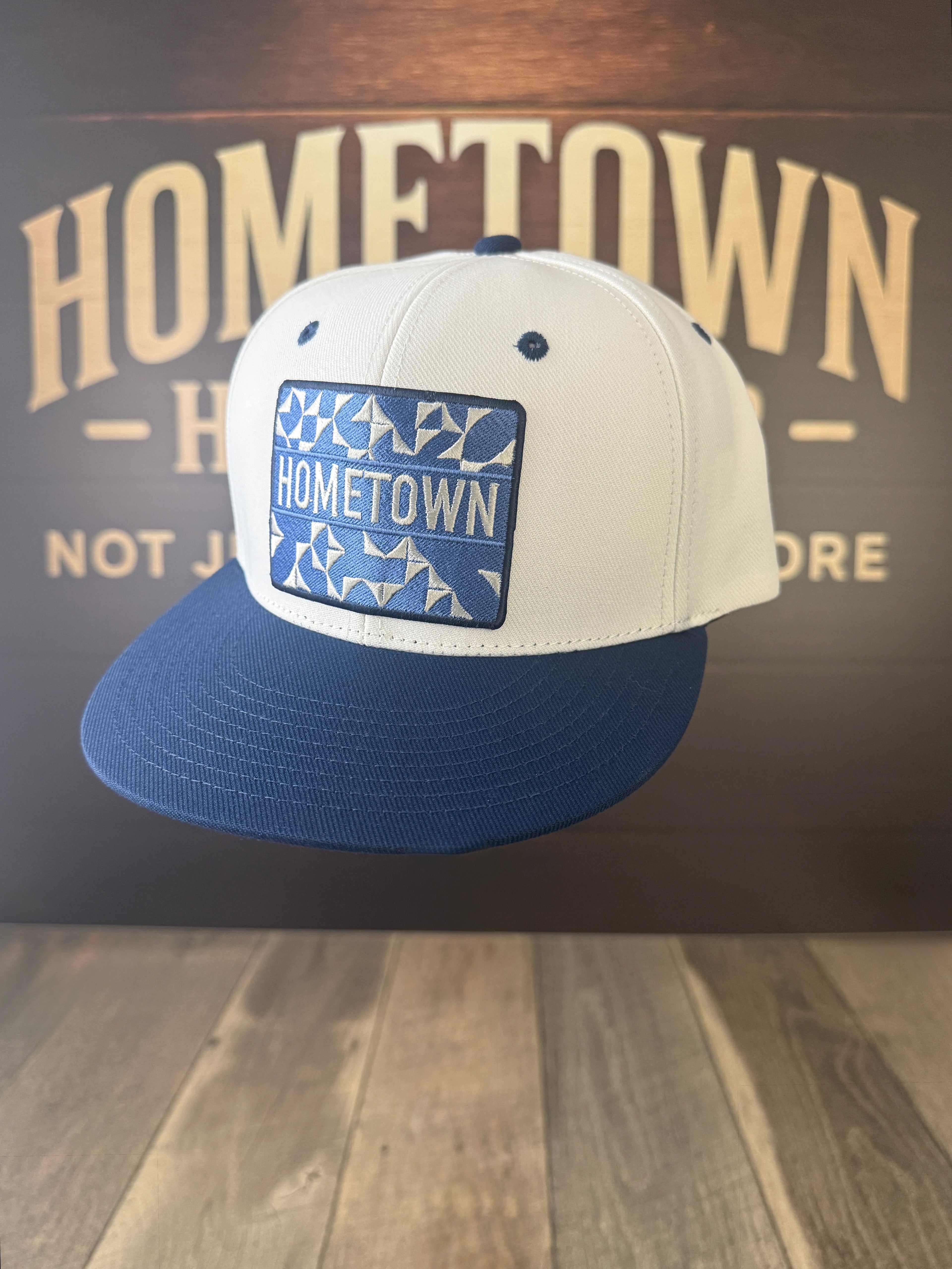 Blue flatbill hat with custom patch, featuring Hometown Granny's Quilt Pattern.