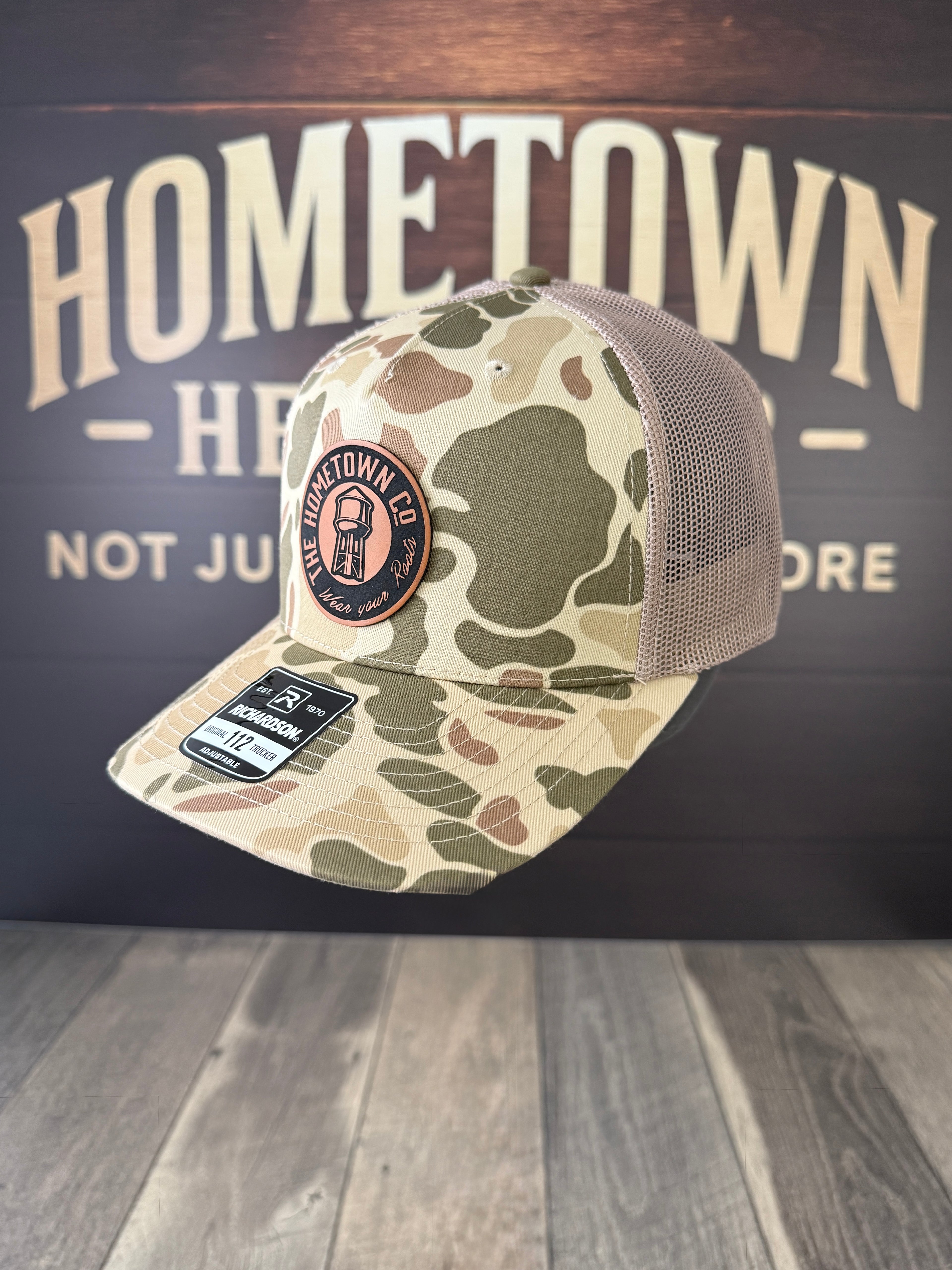 Camo trucker hat with round Signature Leatherette patch, Rawhide to Black.
