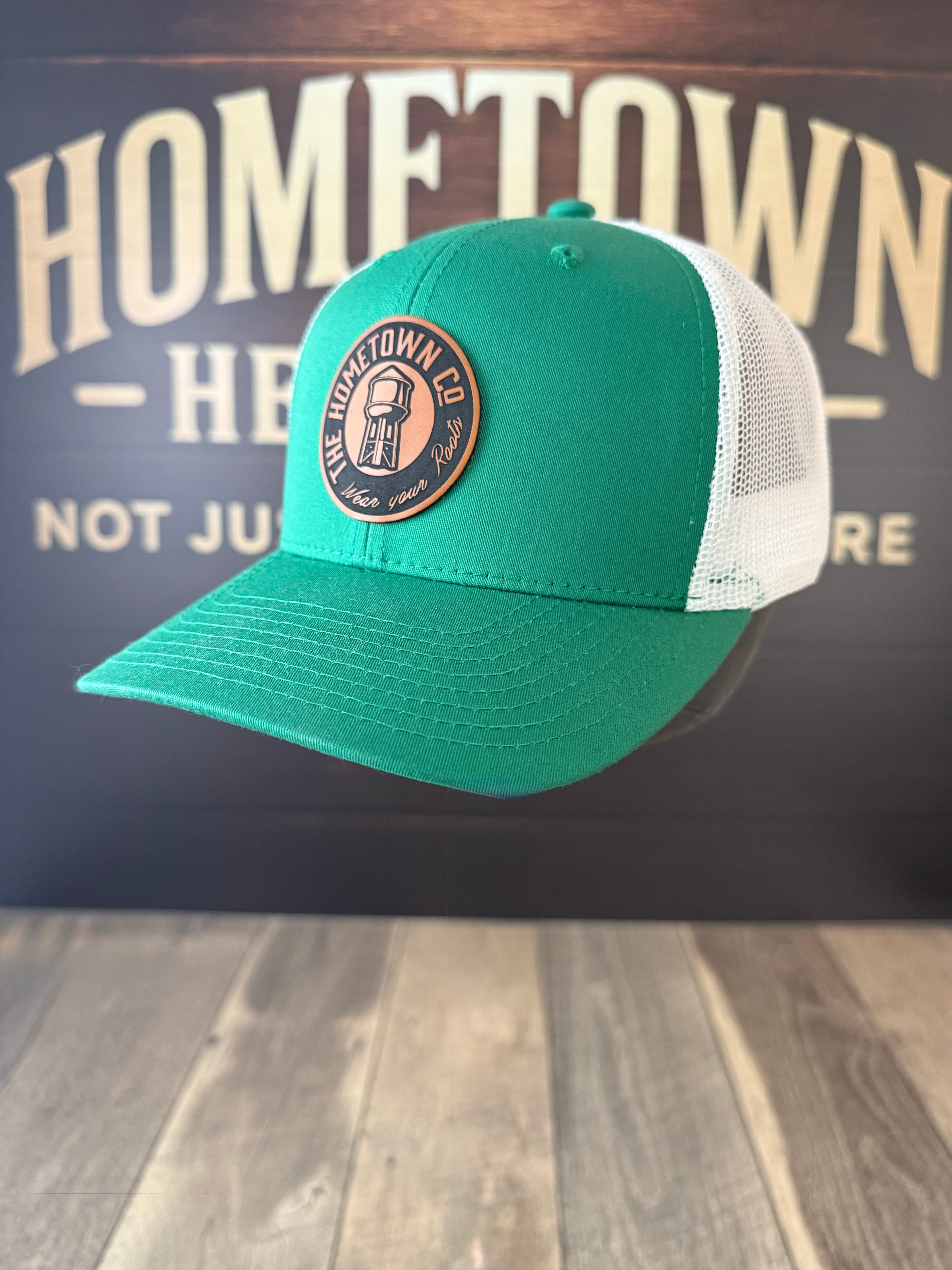 Green and white trucker hat with round water tower patch on the front.